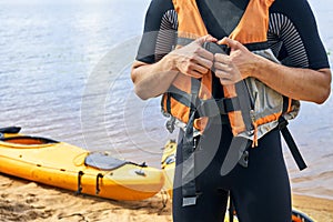 Young hiker wearing wetsuit putting on a life vest