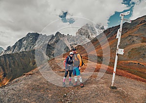 Young hiking couple in Guli Pass under the double peak Ushba in Svaneti region of Georgia