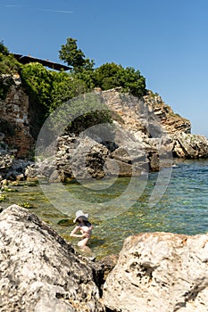 Young hippie beautiful nudist woman on the sea shore in summer time having relaxing time in water on o sunny day