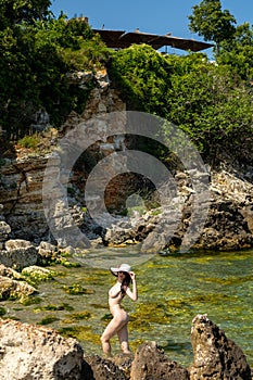 Young hippie beautiful nudist woman on the sea shore in summer time having relaxing time in water on o sunny day