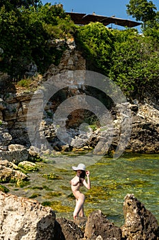 Young hippie beautiful nudist woman on the sea shore in summer time having relaxing time in water on o sunny day