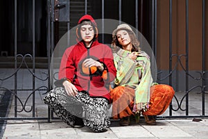 Young hippie couple sitting on the sidewalk