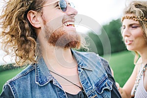 Young hippie male with beard hugging curly female outdoors