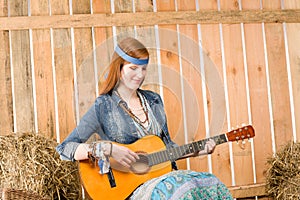 Young hippie woman play guitar in barn