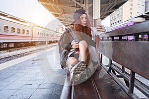 Young hipster asian woman taking selfie or using mobile smart phone video call with bad mood face at train station platform
