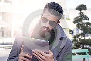 Young hipster businessman consults his laptop in the heart of ci