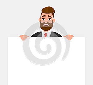 Young hipster businessman showing blank white poster or paper copy space area. Happy trendy person holding empty banner.