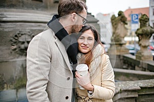 Young hipster couple with coffee kissing, hugging in old town