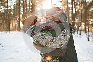 Young hipster couple hugging each other in winter forest