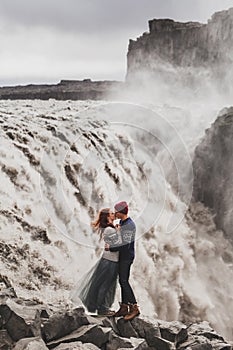 Young hipster couple in love kissing near famous Iceland Dettifoss waterfall