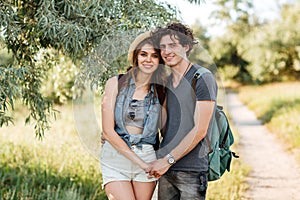 Young hipster couple standing against trees on the background