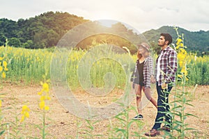 Young hipster couple taking a walk on beautiful flower field.