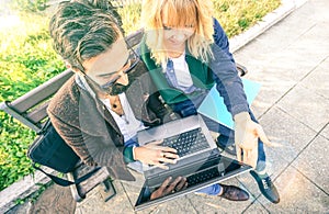 Young hipster couple using computer laptop in urban outdoor location - Modern fun concept with millenials on new trends and photo