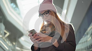 A young hipster female using app on the smartphone in the big mall