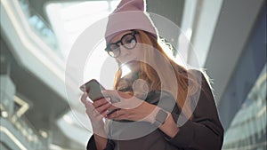 A young hipster female using app on the smartphone in the big mall