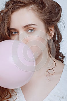 Young hipster girl blowing bubble gum on white