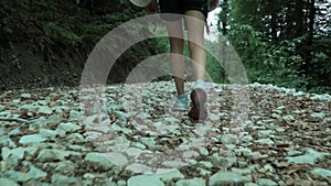 Young hipster girl hike by white cobblestones track in the summer forest, taken from the shoes to the head