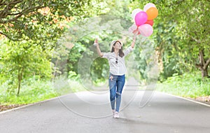 Young hipster girl holding balloon walk on the road,