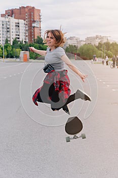 A young hipster girl jumps on a longboard. The concept of summer skateboarding, a hobby