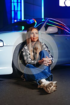 Young hipster girl near old sport car at night city