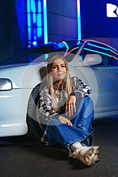 Young hipster girl near old sport car at night city