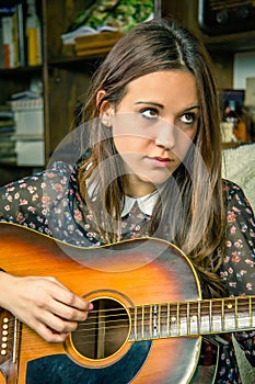 Young hipster girl playing acoustic guitar at home