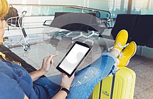 Young hipster girl sitting at airport and put feet in yellow boot on suitcase traveling in Europe, female hands using app