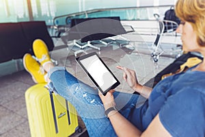 Young hipster girl sitting at airport in yellow boot on suitcase traveling in Europe, female hands texting message on gadget