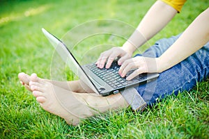 Young hipster girls feet with laptop in a park