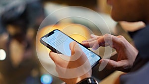 Young hipster guy texting with his mobile phone at the bar. Stock. A young man with a phone in his hands in a cafe