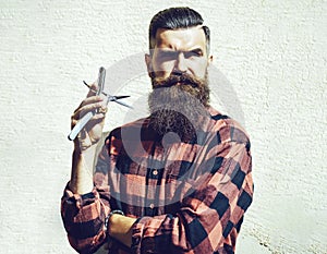 Young hipster hairdresser. Bearded man in barber shop. Barber scissors and straight razor, barber shop. Portrait bearded