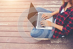 Young hipster hands typing laptop sitting on pier lake, relaxing