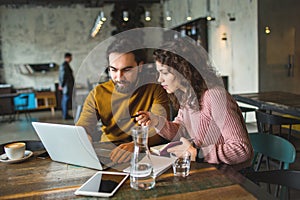 Young hipster male and female working laptop together in cafe