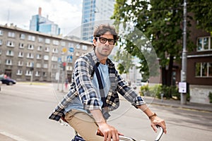 Young hipster man with bag riding fixed gear bike