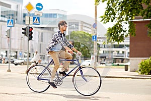 Young hipster man with bag riding fixed gear bike