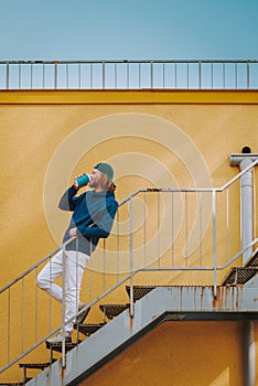 Young hipster man drinking coffee on stairs