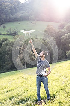 Young hipster man with flying drone. Sunny green nature.