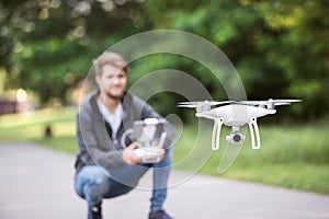 Young hipster man with flying drone. Sunny green nature.