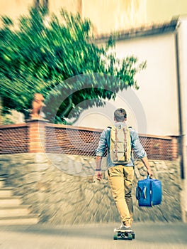 Young hipster man moving with his longboard and luggage