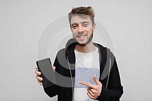 Young hipster man pointing at his phone. Casual guy showing something on his phone screen. Hipster gesturing and smiling with his