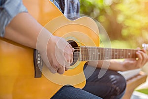 Young hipster man practiced guitar in the park,happy and enjoy playing guitar.