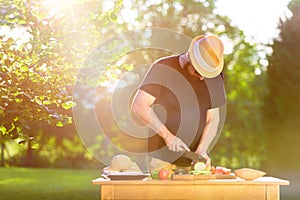 Young hipster man preparing food for garden grill party, summer barbecue
