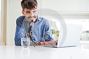 Young hipster man recording podcast using laptop, broadcasting an interview using microphone