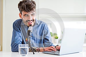 Young hipster man recording podcast using laptop, broadcasting an interview using microphone