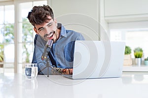 Young hipster man recording podcast using laptop, broadcasting an interview using microphone