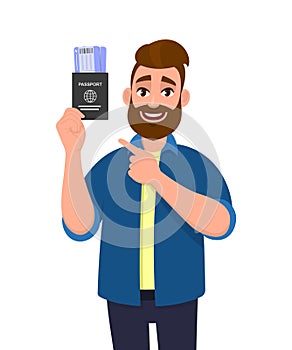 Young hipster man showing passport tickets and pointing finger. Trendy person holding boarding pass. Travel and tourism concept.