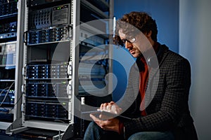 Young hipster man using digital tablet working in server room