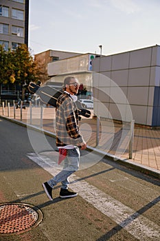 Young hipster man wearing casual attire walking with skateboard