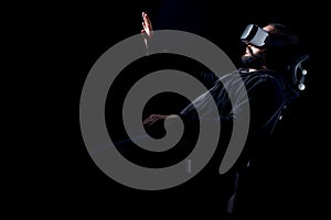 Young hipster man wearing virtual reality goggles. Black background studio VR concept