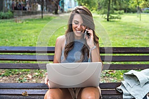 Young hipster millennial freelance woman with cool attitude, expatriate exchange student, sitting in park working online on laptop photo